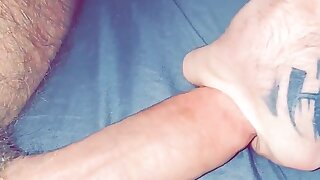 Hairy guy with tattoos strokes big cock up close