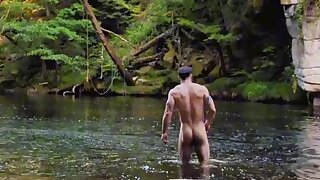 Muscular guy strips down to cool off in the river. Exposing his nude body in nature makes his cock hard, so he shamelessly jerks off and cums right there in the open (exhibitionism)